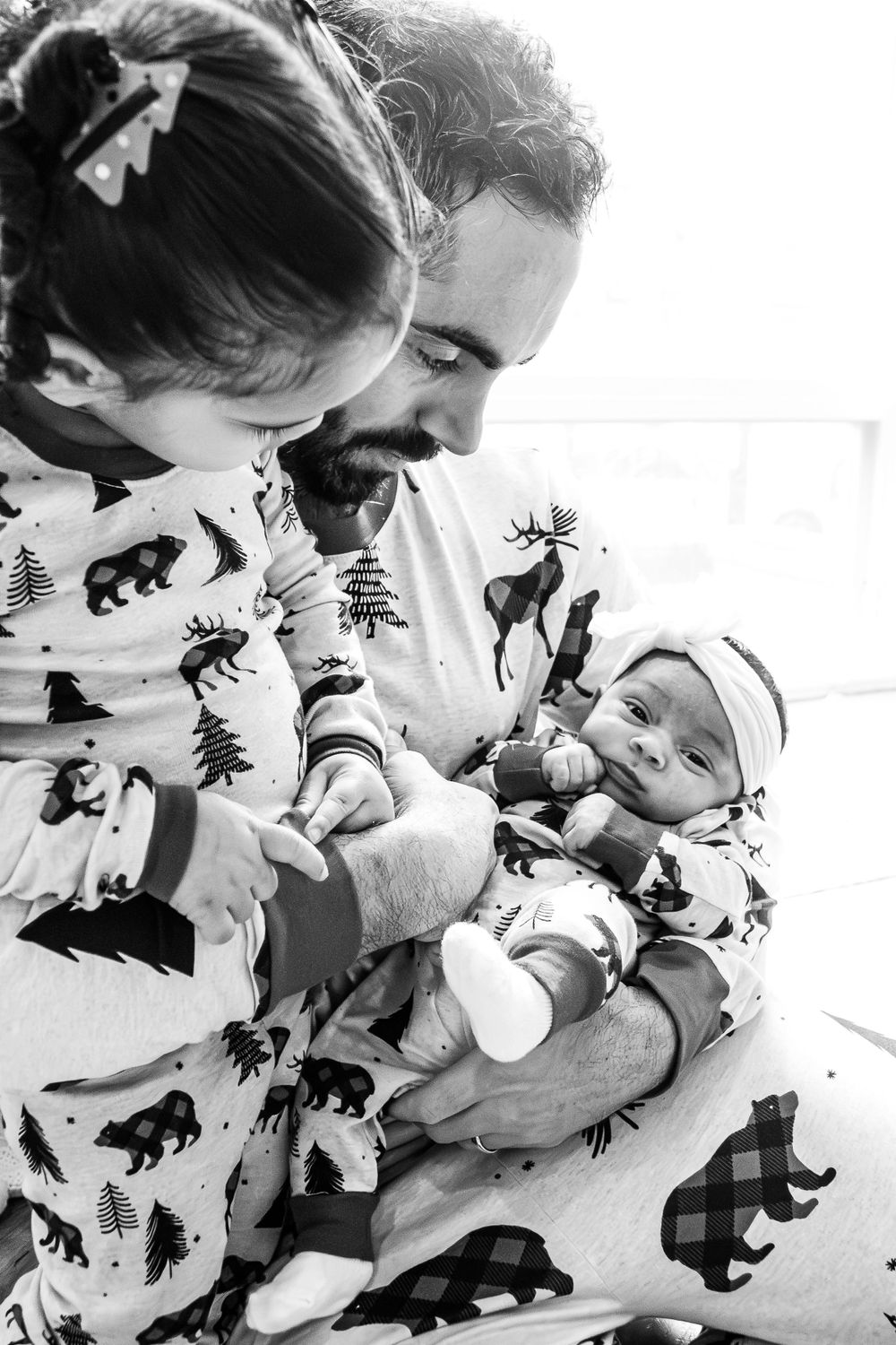 A tender family moment captured in black and white with everyone wearing matching patterned pajamas.