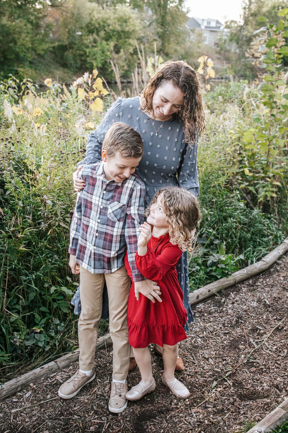 A sweet outdoor moment captured in a natural garden setting with fallen leaves and greenery in the background.