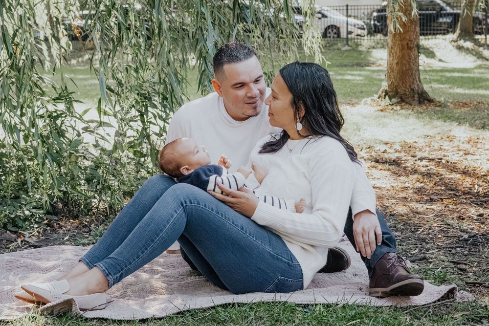 A couple in white shirts and jeans relaxes together on grass in a romantic outdoor photo session.
