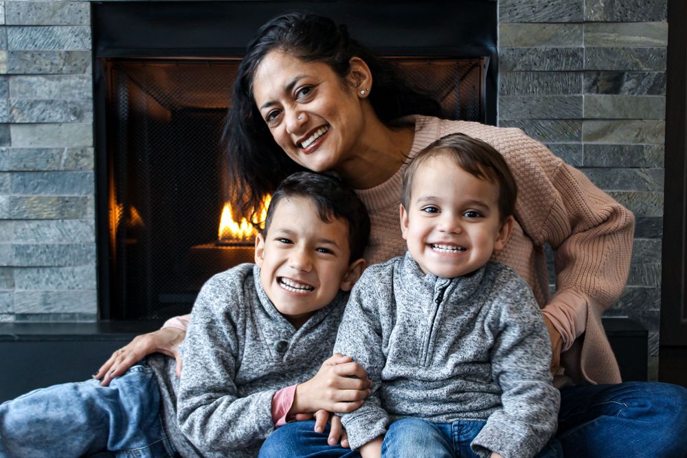 A cozy family moment by the fireplace wearing matching gray sweaters.