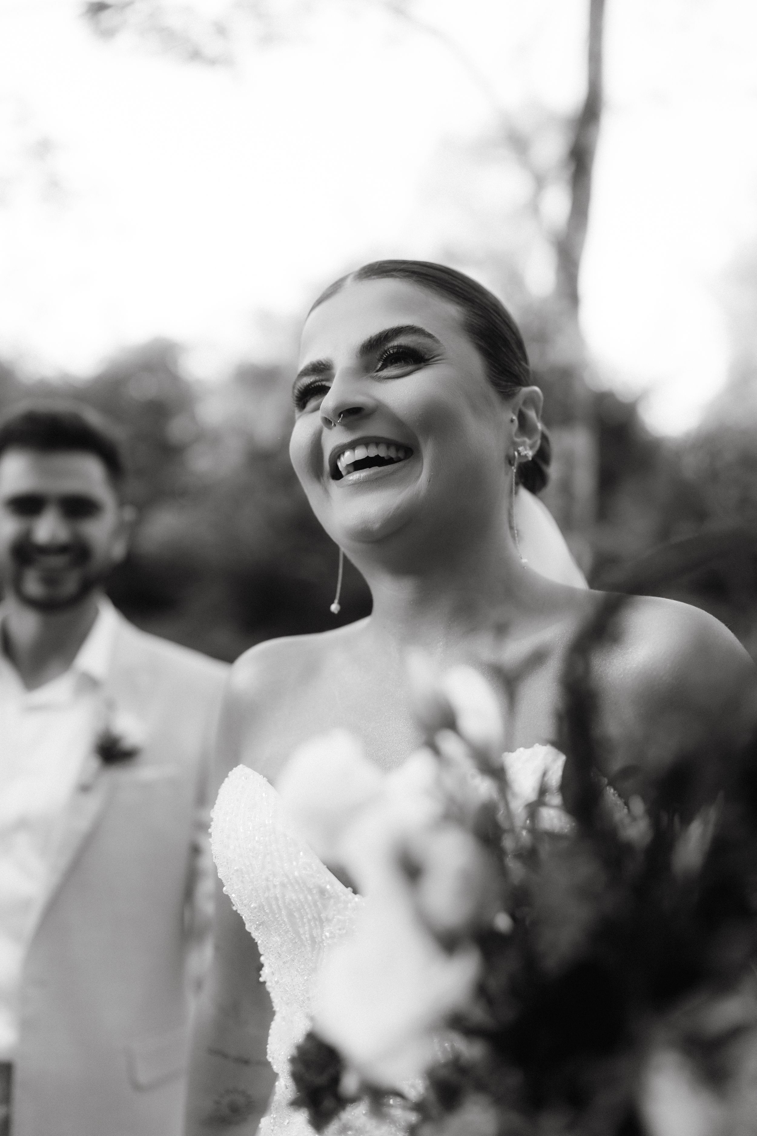 Wedding guests react with laughter and joy during an outdoor ceremony.