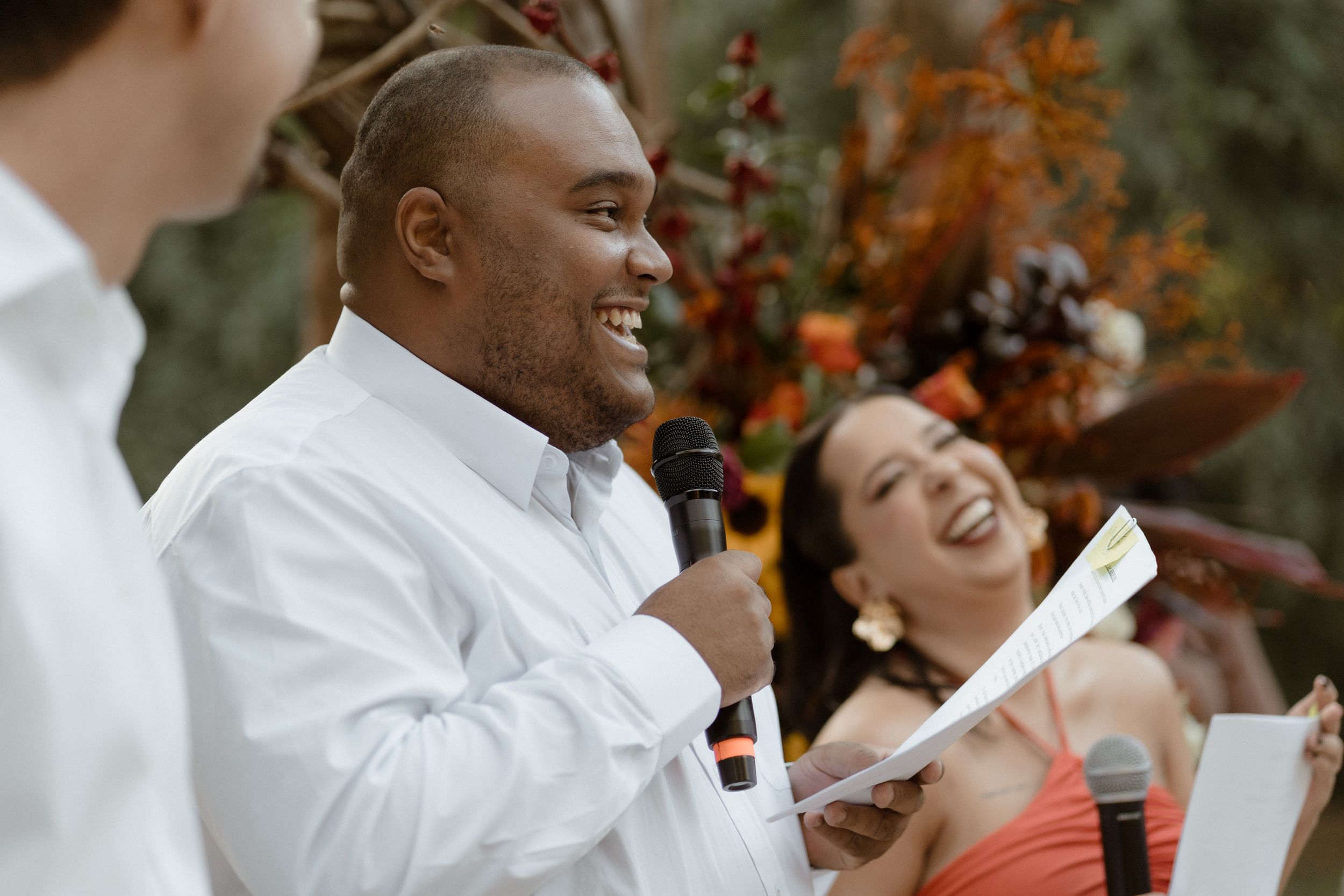 Wedding guests share emotional reactions during outdoor ceremony speeches.