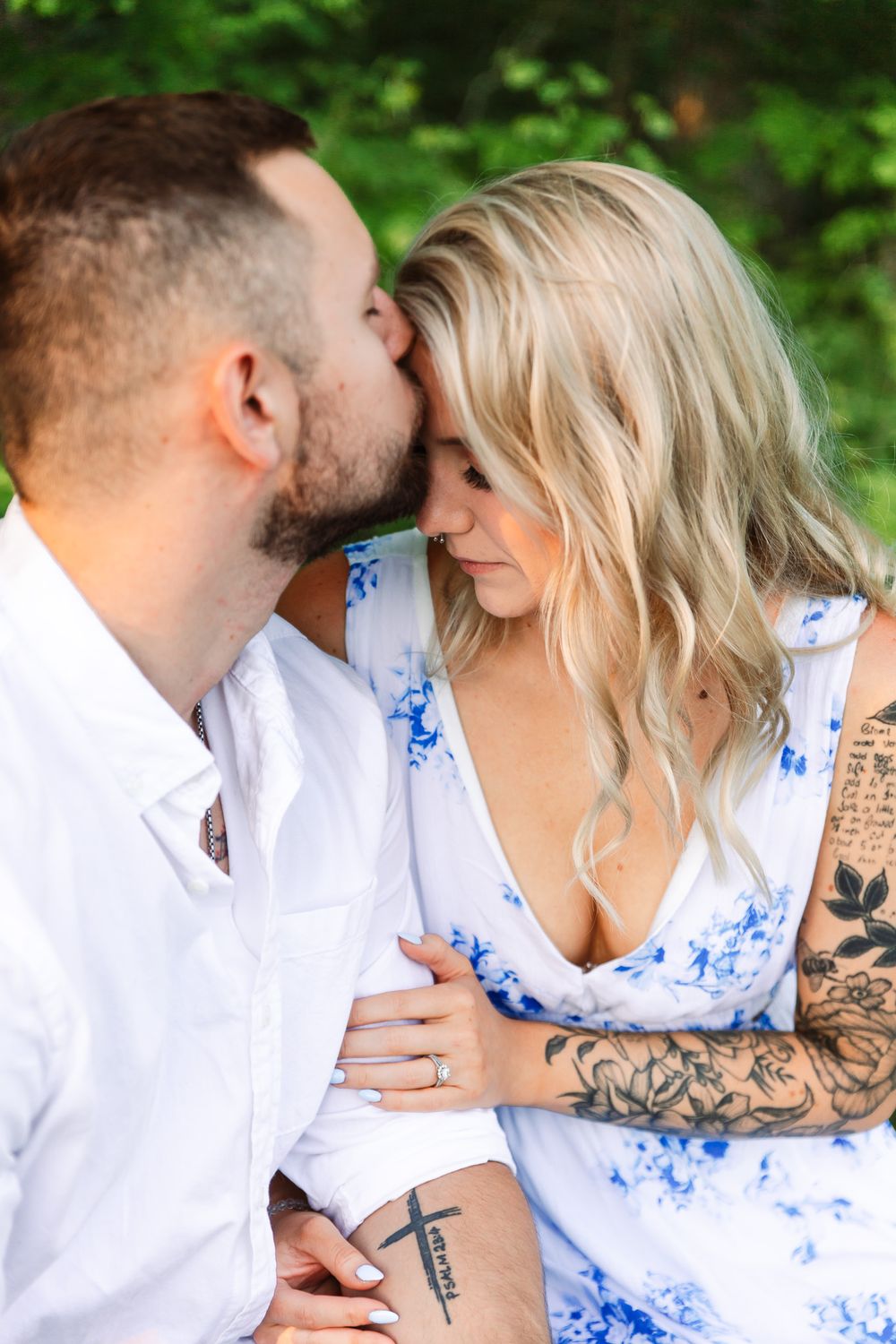 Close-up romantic moments between couple wearing white shirt and blue floral dress outdoors.
