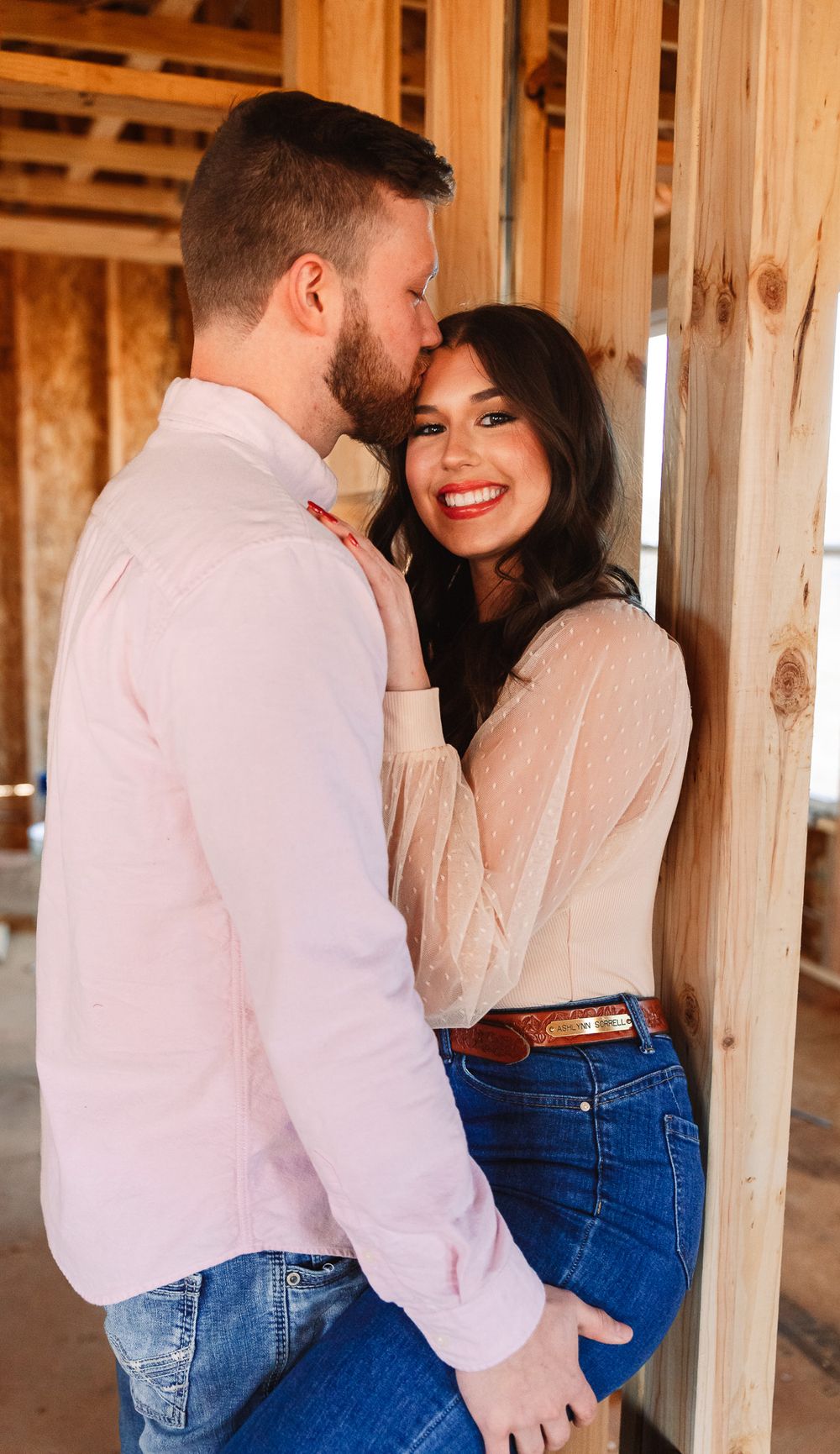 Couple in white shirts and jeans sharing intimate moments in a wooden structure.