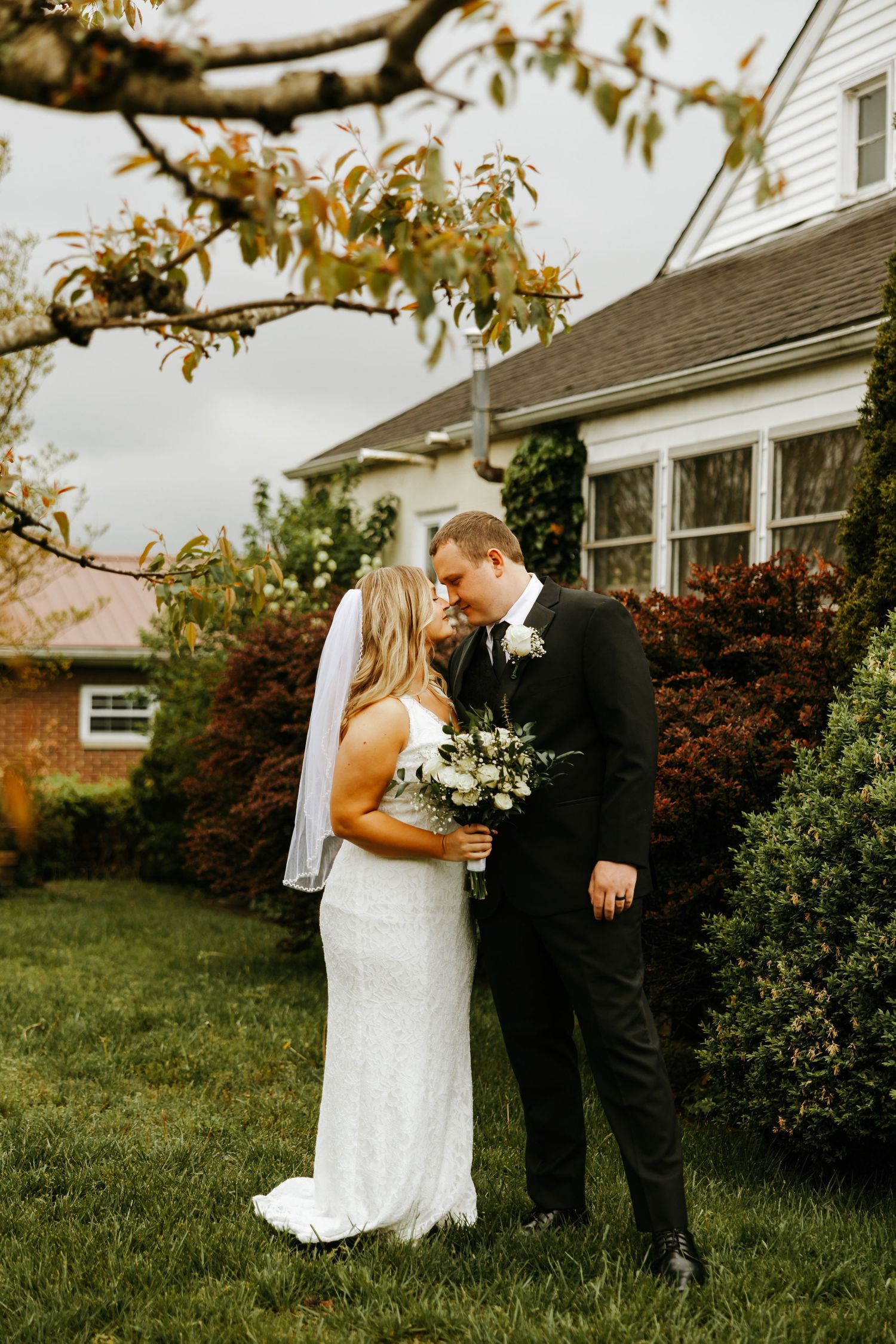 Couple dancing and twirling in front of a rustic wooden barn during golden hour at their wedding celebration.
