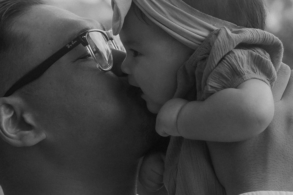 An intimate black and white close-up portrait showing a tender family moment.