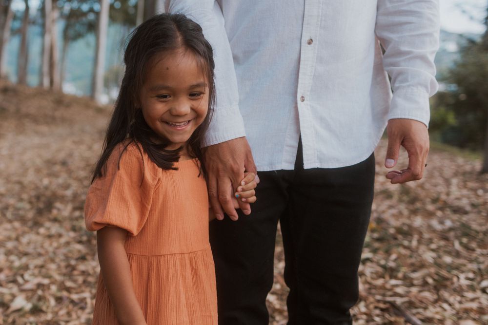 A heartwarming moment captured between parent and child holding hands in a forest setting.
