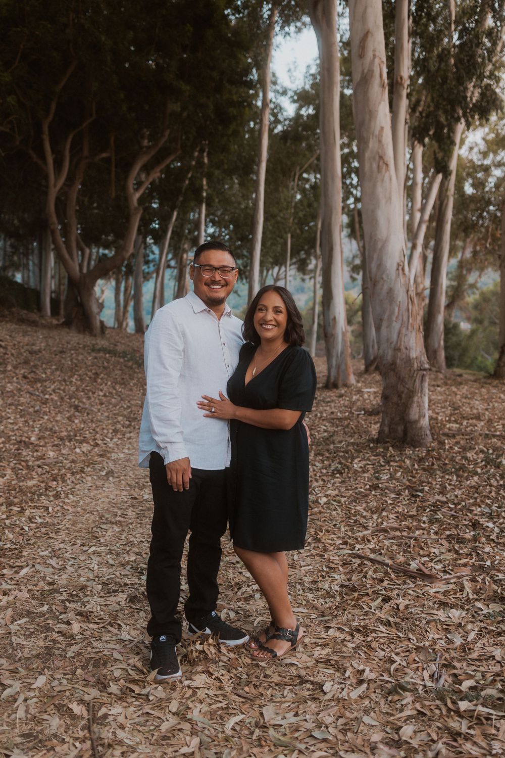 A romantic couple's portrait in a eucalyptus grove with soft lighting and fallen leaves.