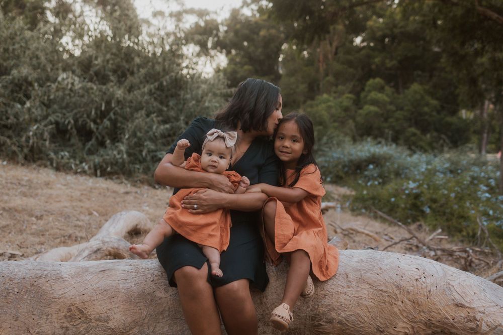 A loving family moment captured on a rocky outcrop surrounded by trees.