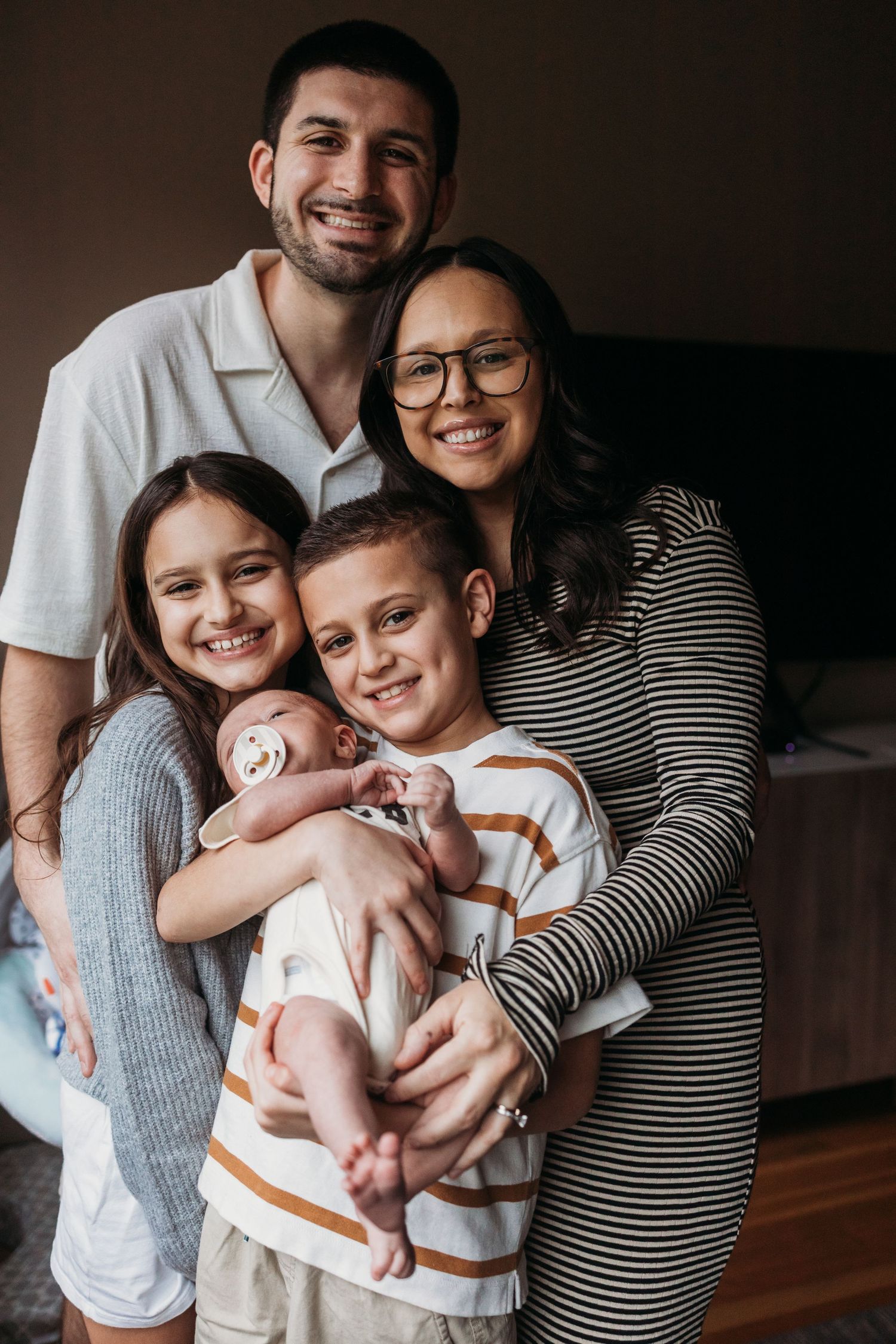 A family of four poses together for a series of intimate indoor portraits showing their closeness and joy.