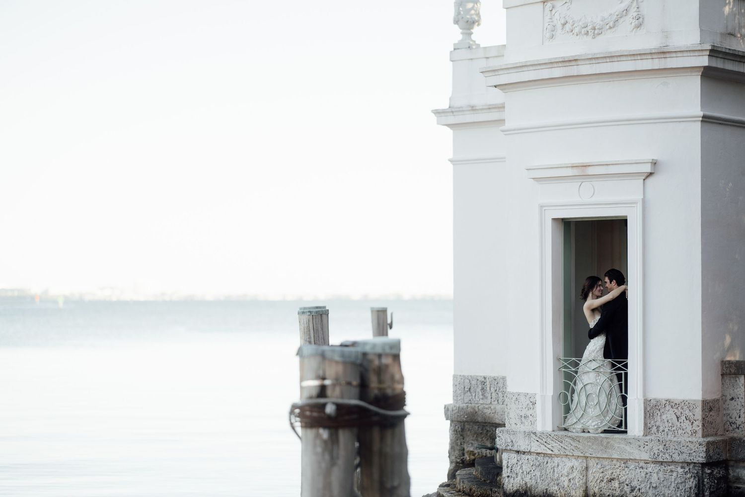 Jupiter FL Wedding photo of a white lighthouse tower stands on a rocky coastline overlooking a misty ocean view. Luxury wedding photographer
