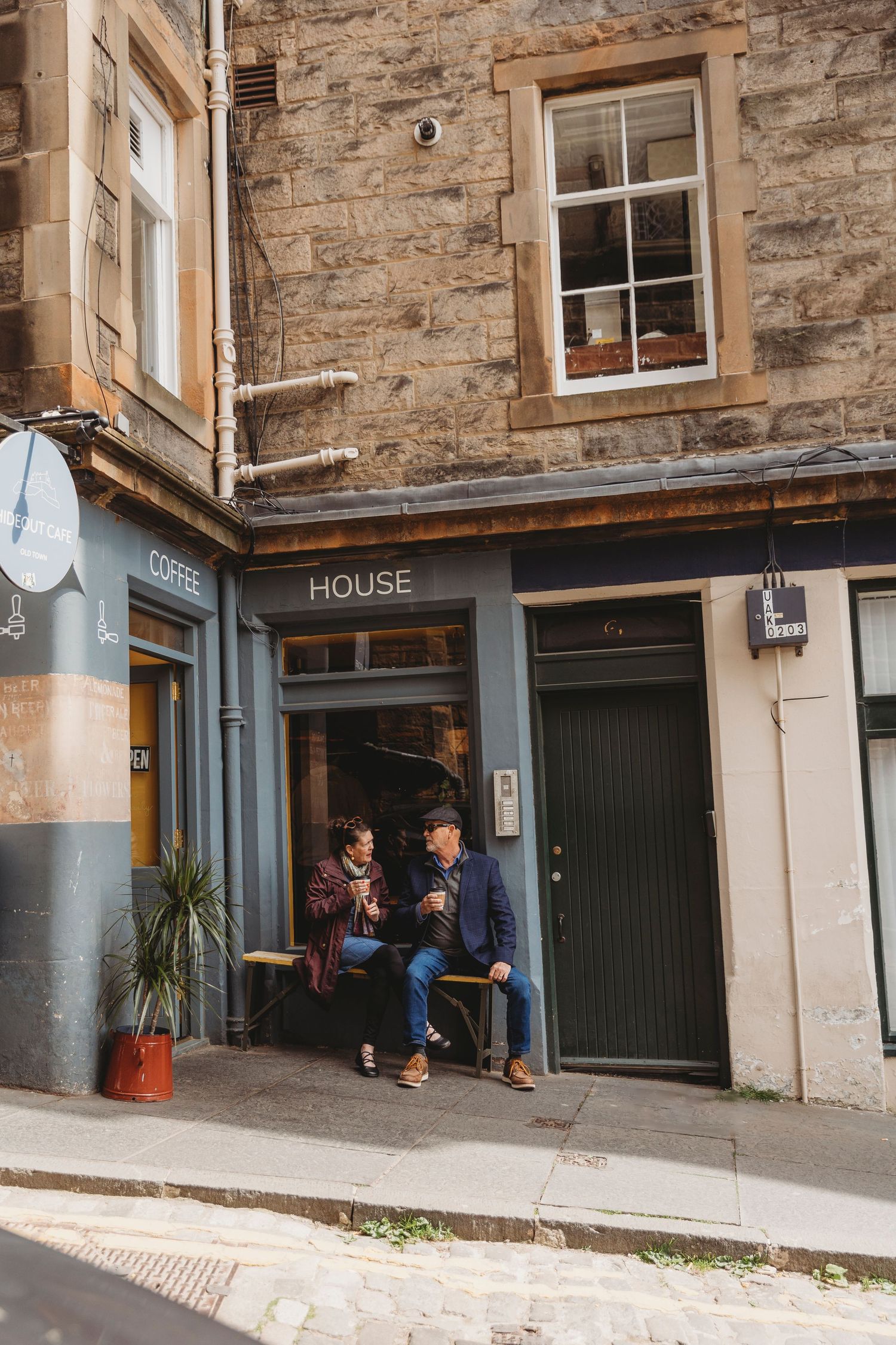 Stone building exterior with green doors and windows along a cobblestone alley in Edinburgh's historic district.