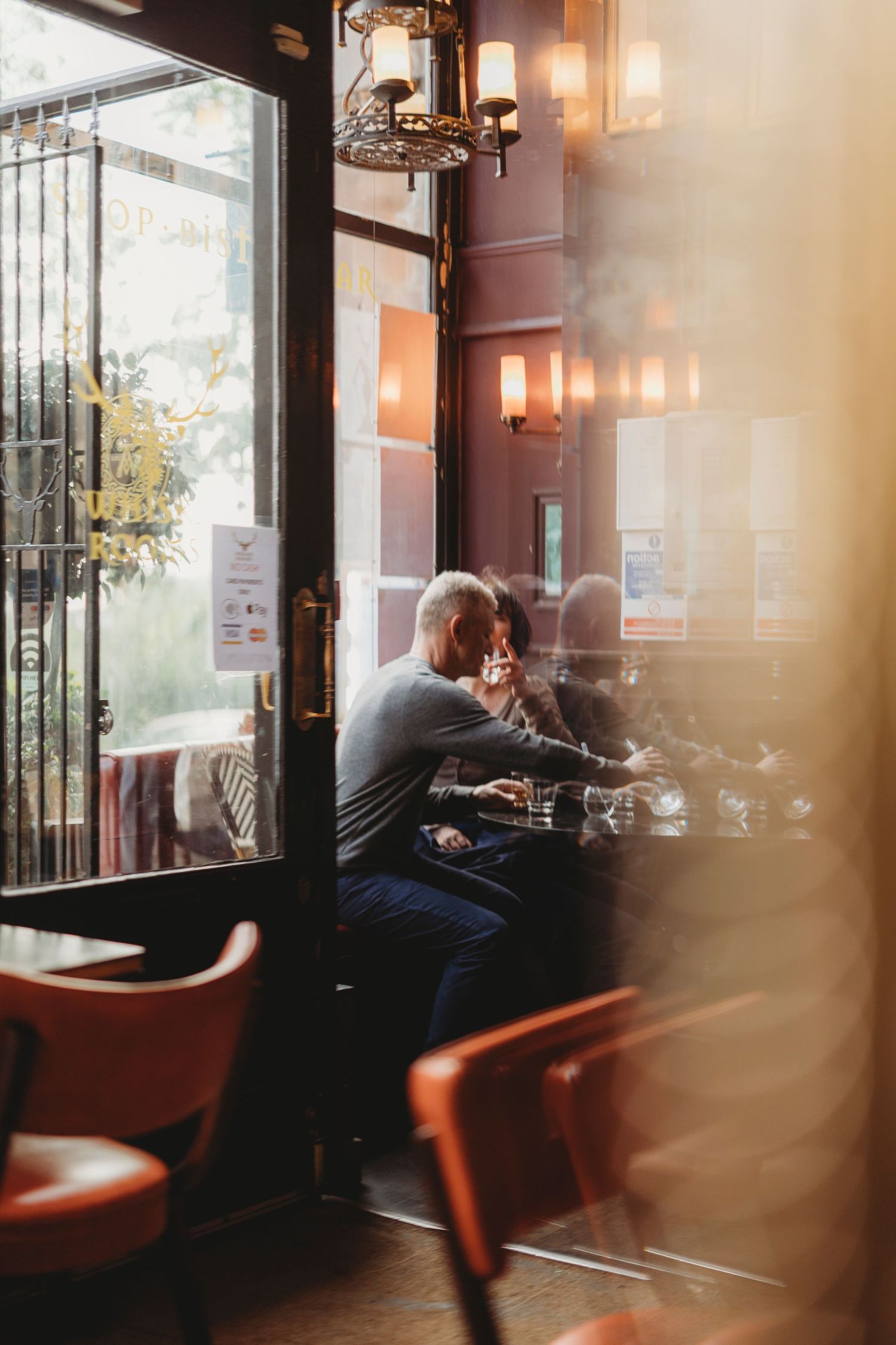 Interior view of a cozy coffee shop with warm lighting and customers seated at window-side tables.