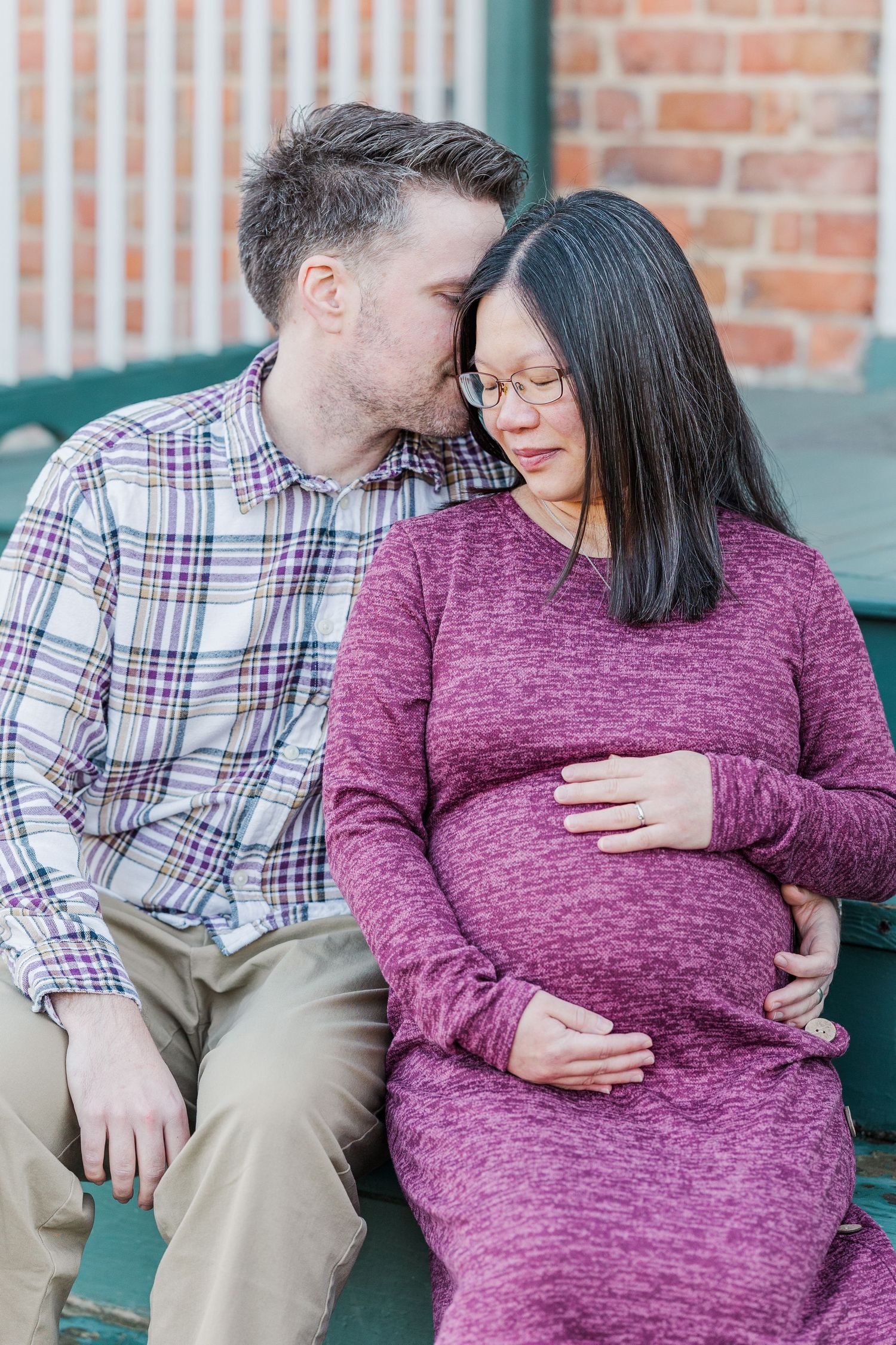 A couple in plaid shirt and burgundy sweater share intimate moments in a series of three photos against a brick wall.