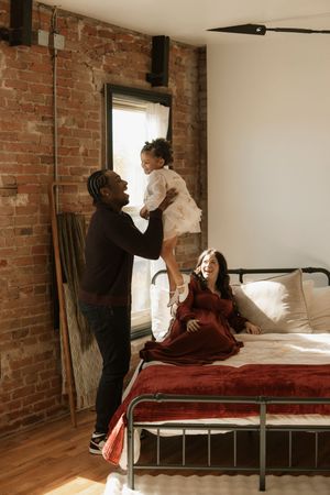 A sequence of photos showing a pillow fight on a bed with exposed brick walls and hardwood floors in the background.