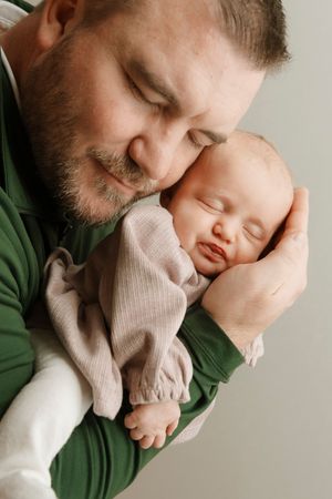 A tender moment captured in a series of intimate photos showing parent and sleeping baby in soft pink and green tones.