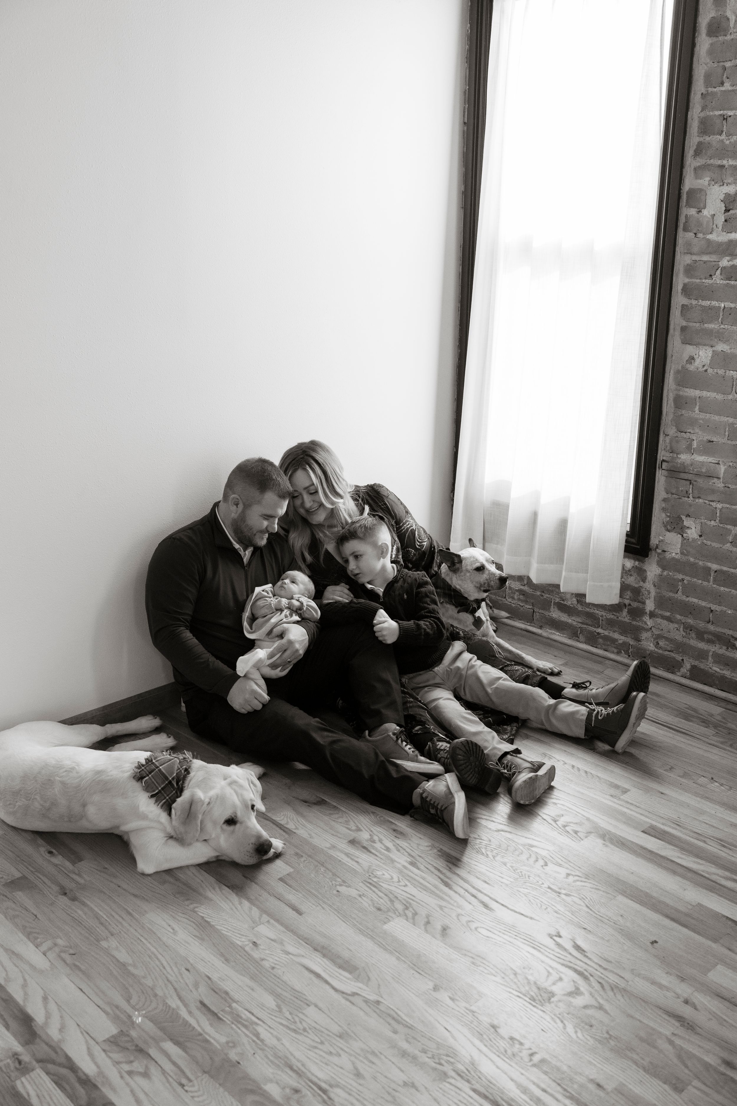 Black and white photo series shows two people playfully wrestling and rolling around on a hardwood floor.