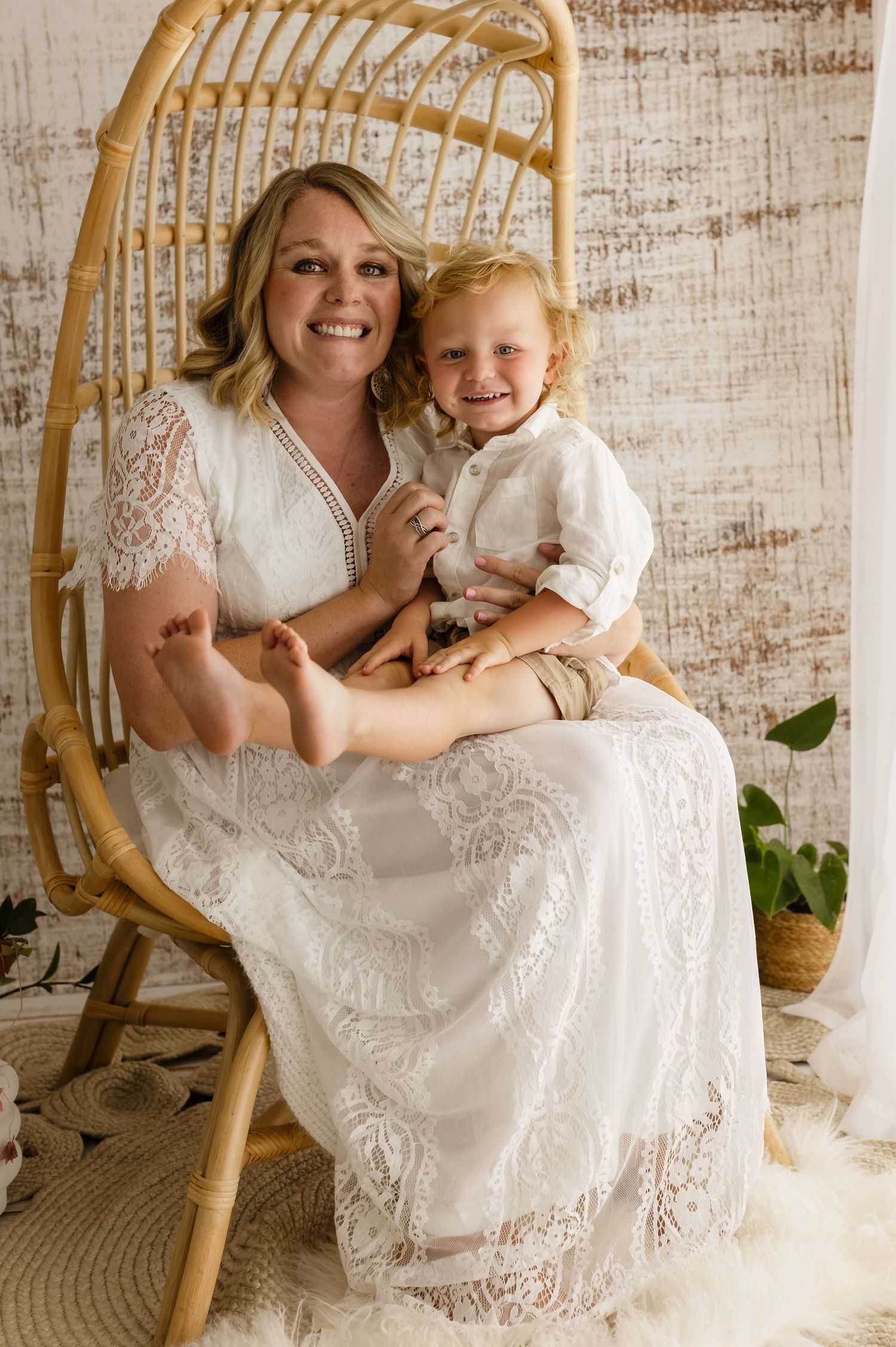 Mom in lace dress hugs her young son against a warm white backdrop, captured by Charlottesville baby, newborn, and family photographer.