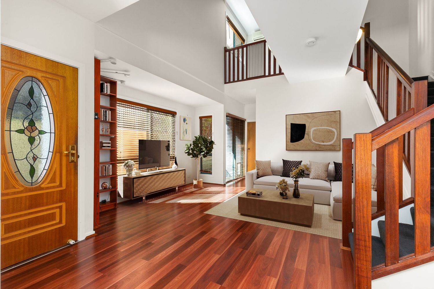 Grand entryway with polished timber floors, stained glass door, and open staircase.