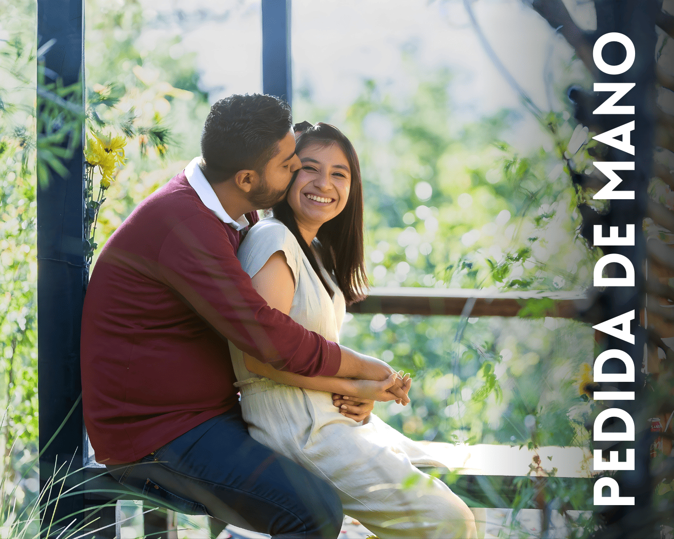 A couple shares a tender moment while sitting together on a porch with lush greenery in the background.