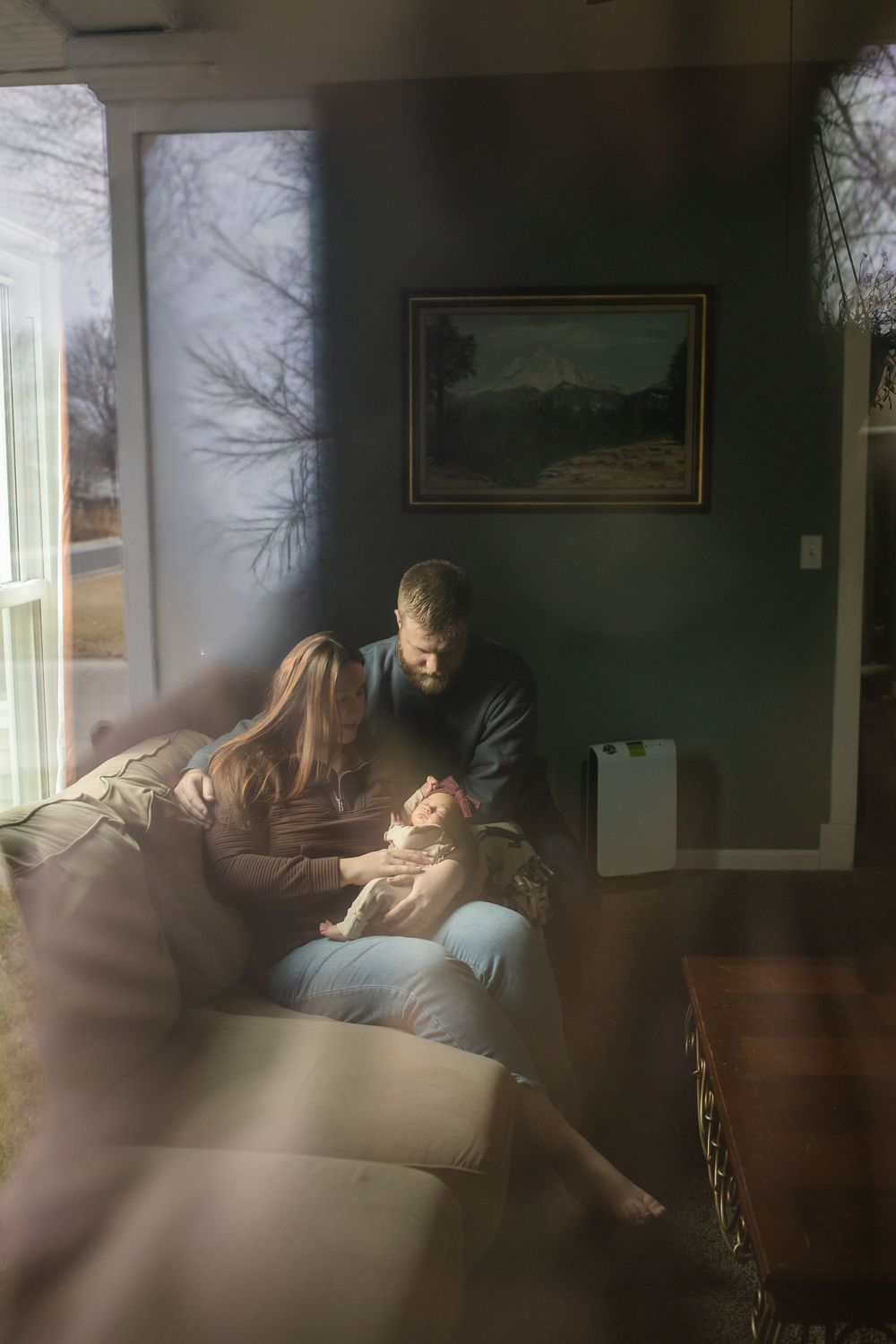 A sequence of four dimly lit photos showing people relaxing on a couch in a living room with natural light from windows.