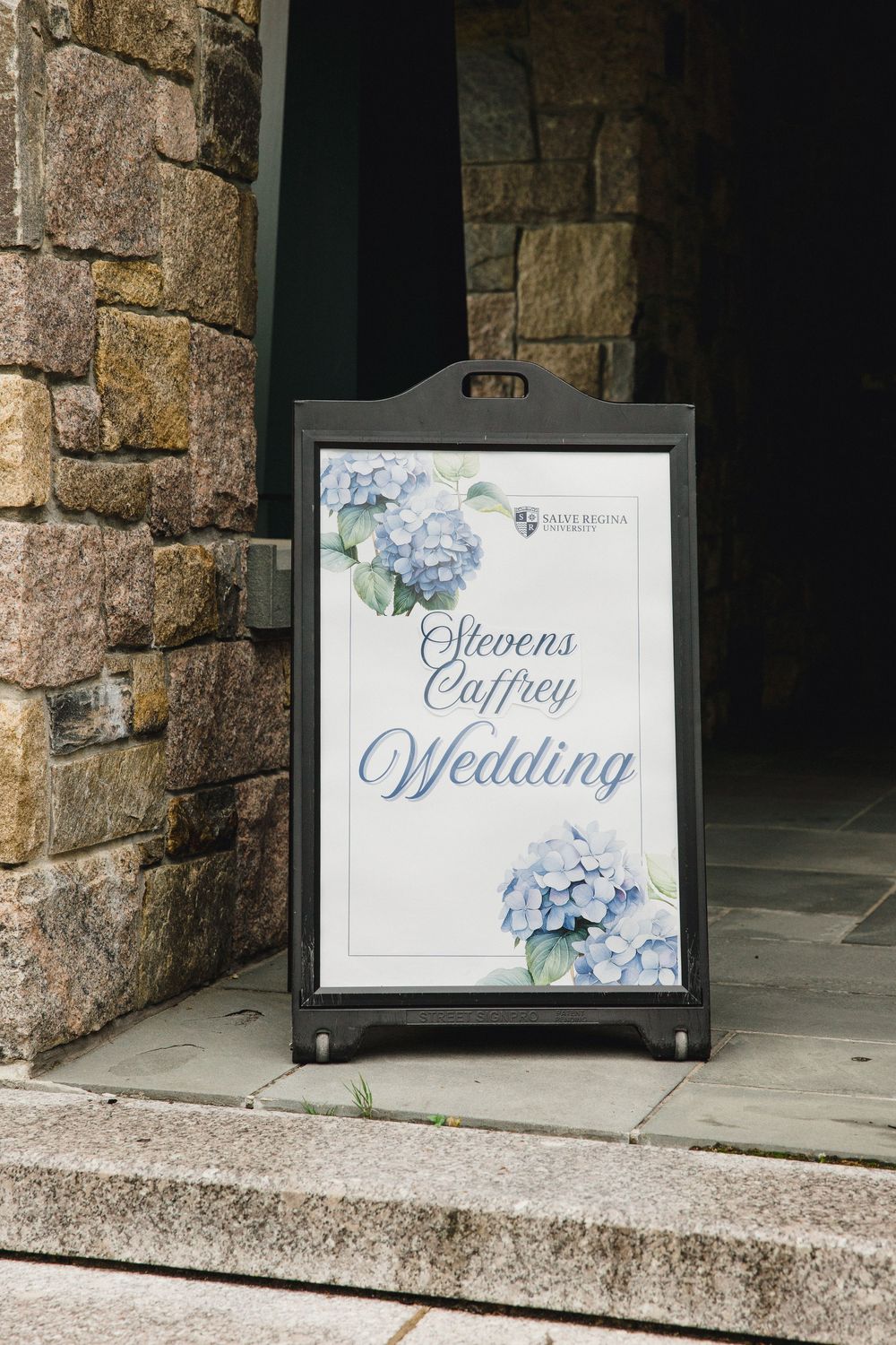 Wedding signage with floral designs displayed on stone steps at an elegant venue.