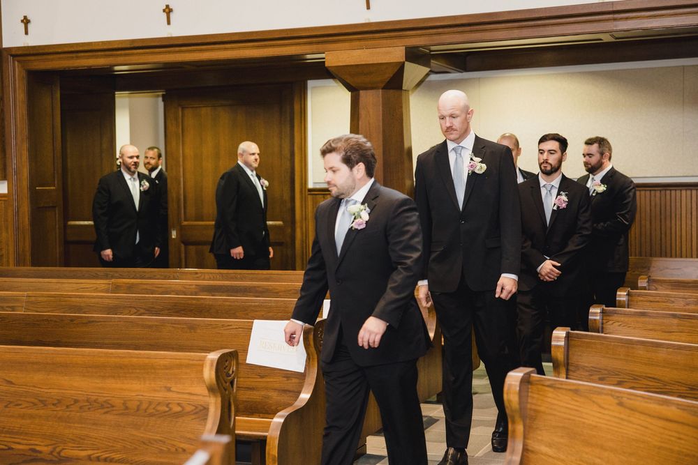 Groomsmen in black tuxedos standing in church sanctuary.