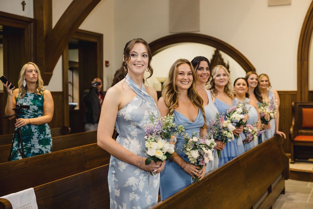 Wedding party members stand in wooden church pews during a joyful celebration ceremony.