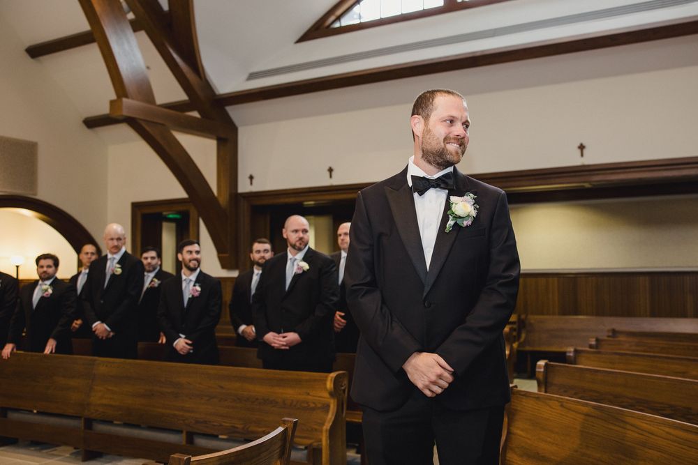 Wedding party standing in church pews during a traditional ceremony.