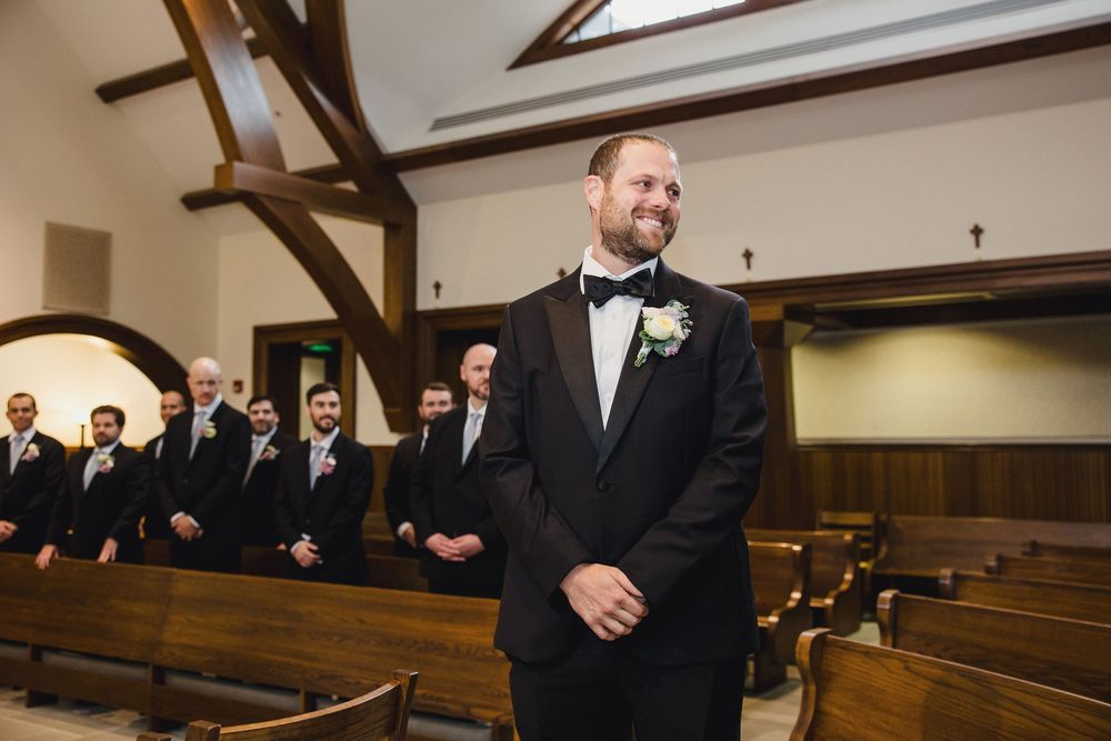 Wedding ceremony in a traditional church sanctuary with wooden pews and exposed beam ceiling architecture.