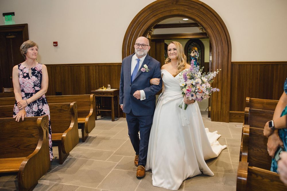 Church wedding ceremony showing guests seated in wooden pews under arched doorways.