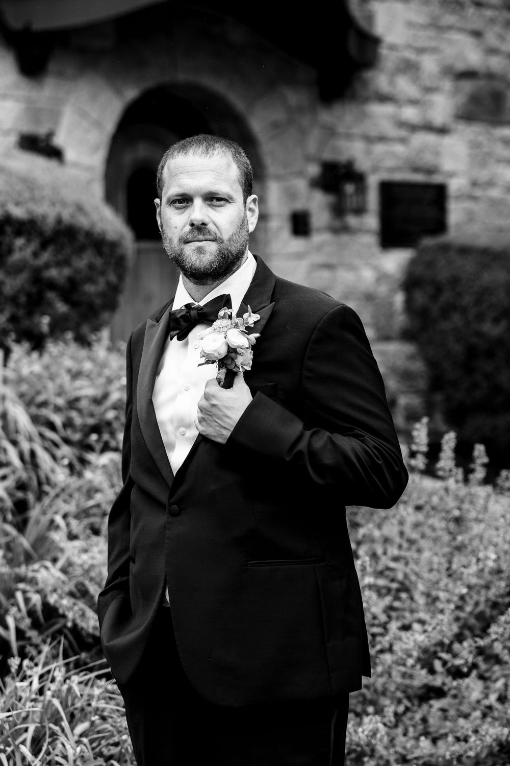 Three black and white portraits of men in formal attire against a stone wall background.