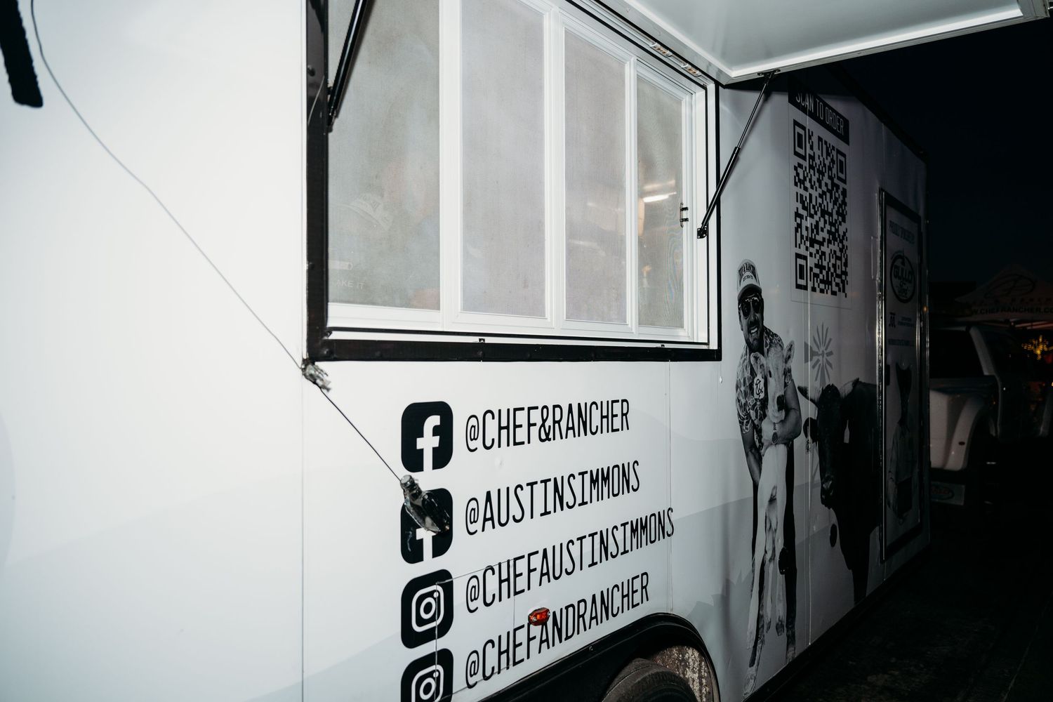 Social media icons and handles displayed in black and white on a wall next to an open window.