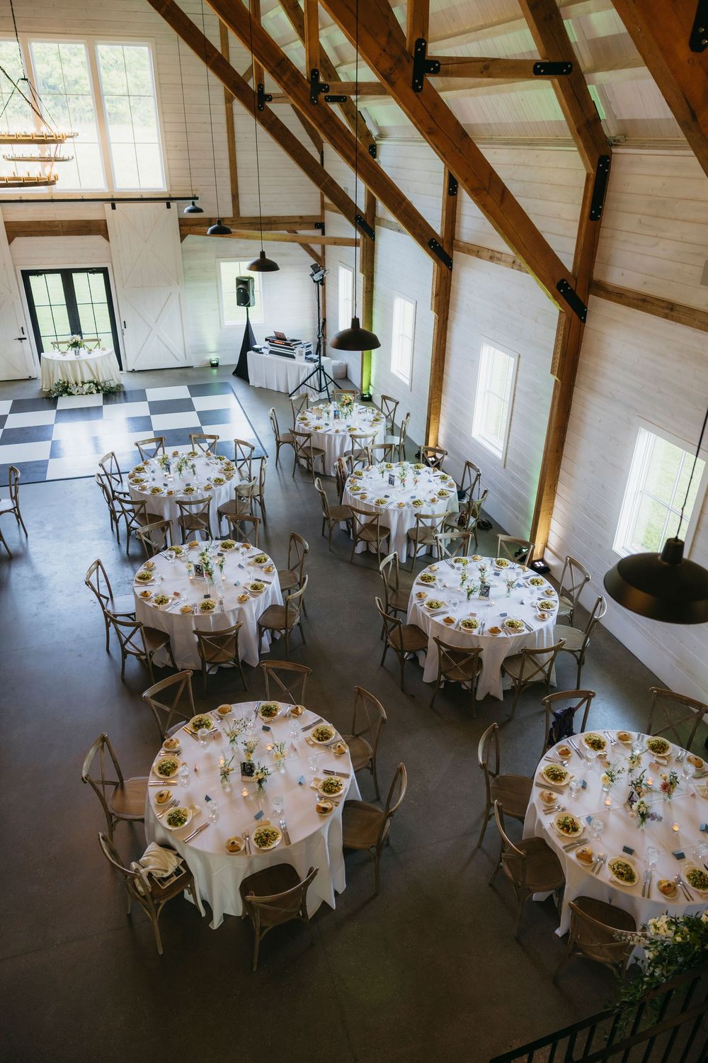 Elegant wedding reception venue with round tables set in white linens and floral centerpieces viewed from above.