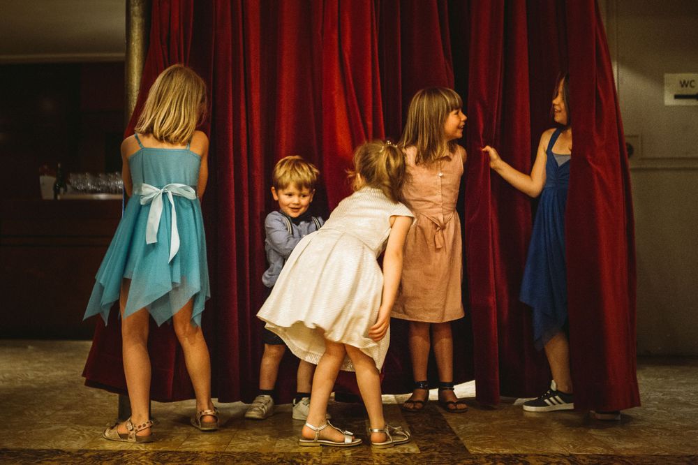 People's feet and legs visible against red stage curtains during a performance.