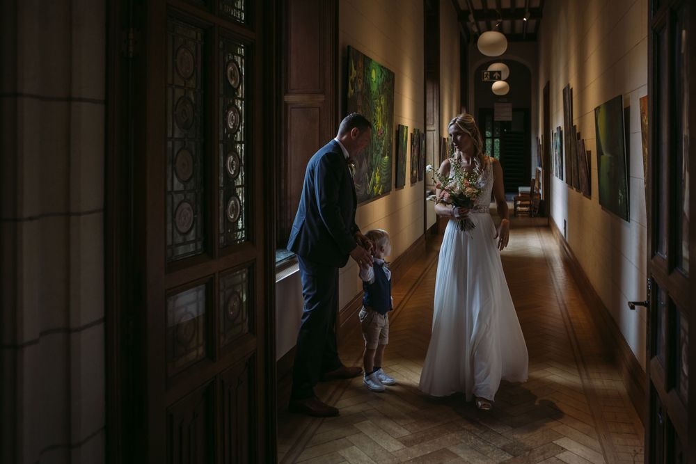 Intimate moment in an elegant hallway with ornate architectural details and natural lighting.