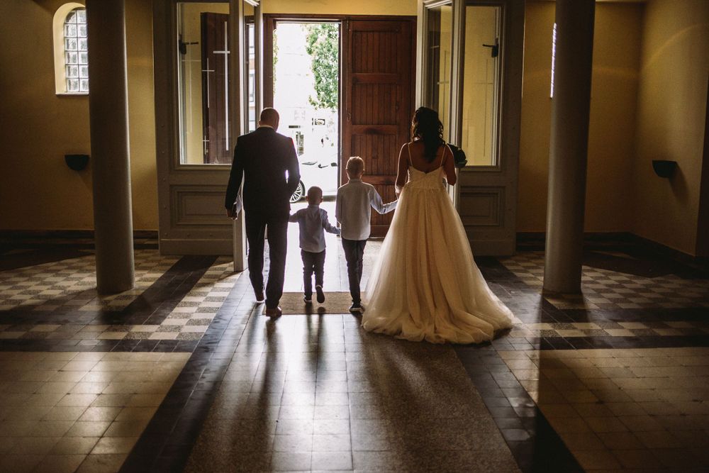 Silhouetted figures walking down a sunlit hallway with beautiful tile flooring.