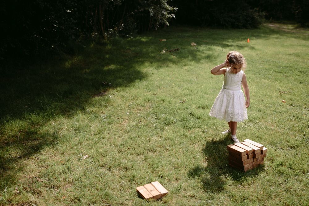 Children playing with boxes on a sunlit grassy lawn.