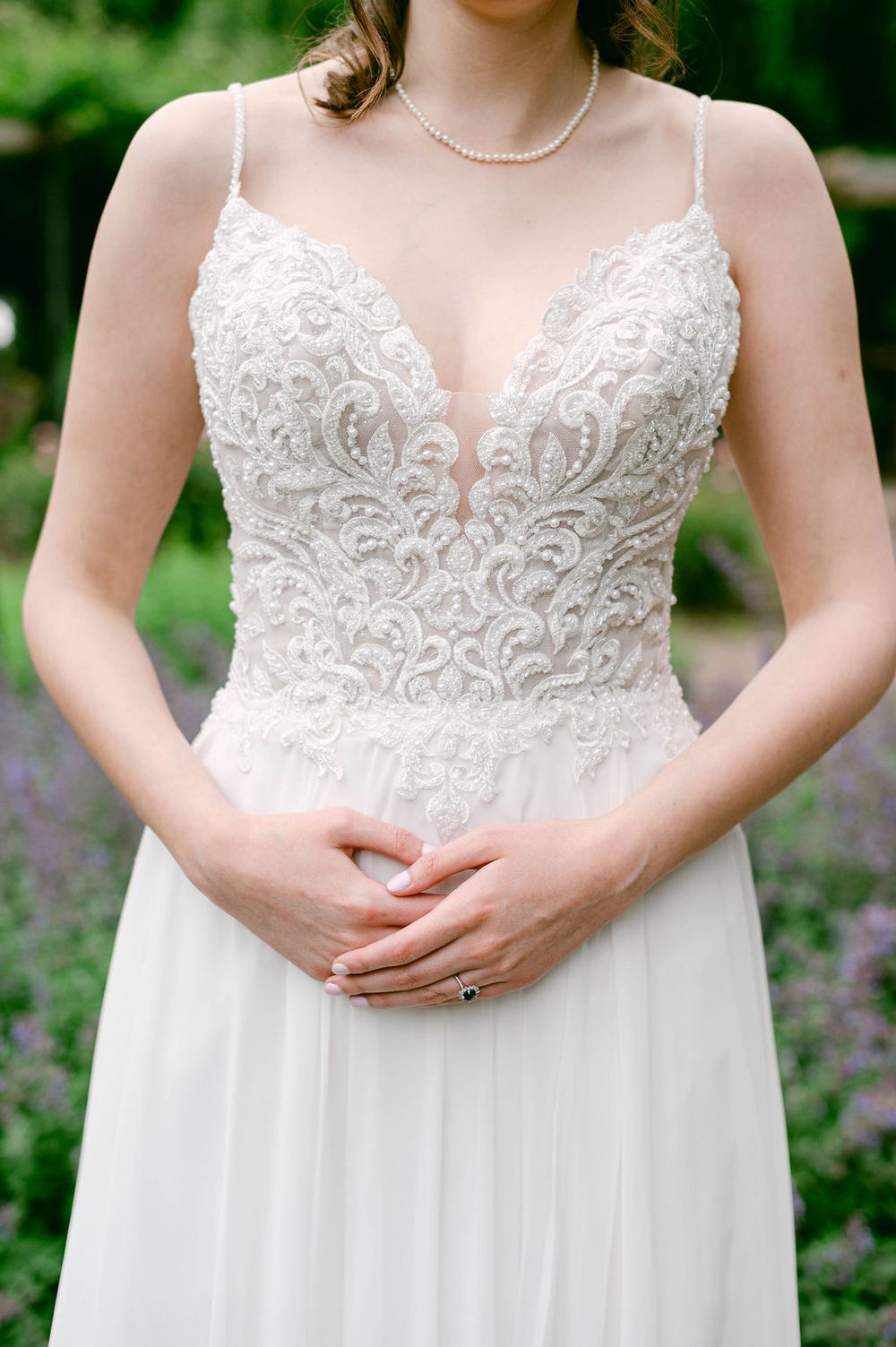 Close-up details of a white lace wedding dress bodice with delicate floral patterns and spaghetti straps.