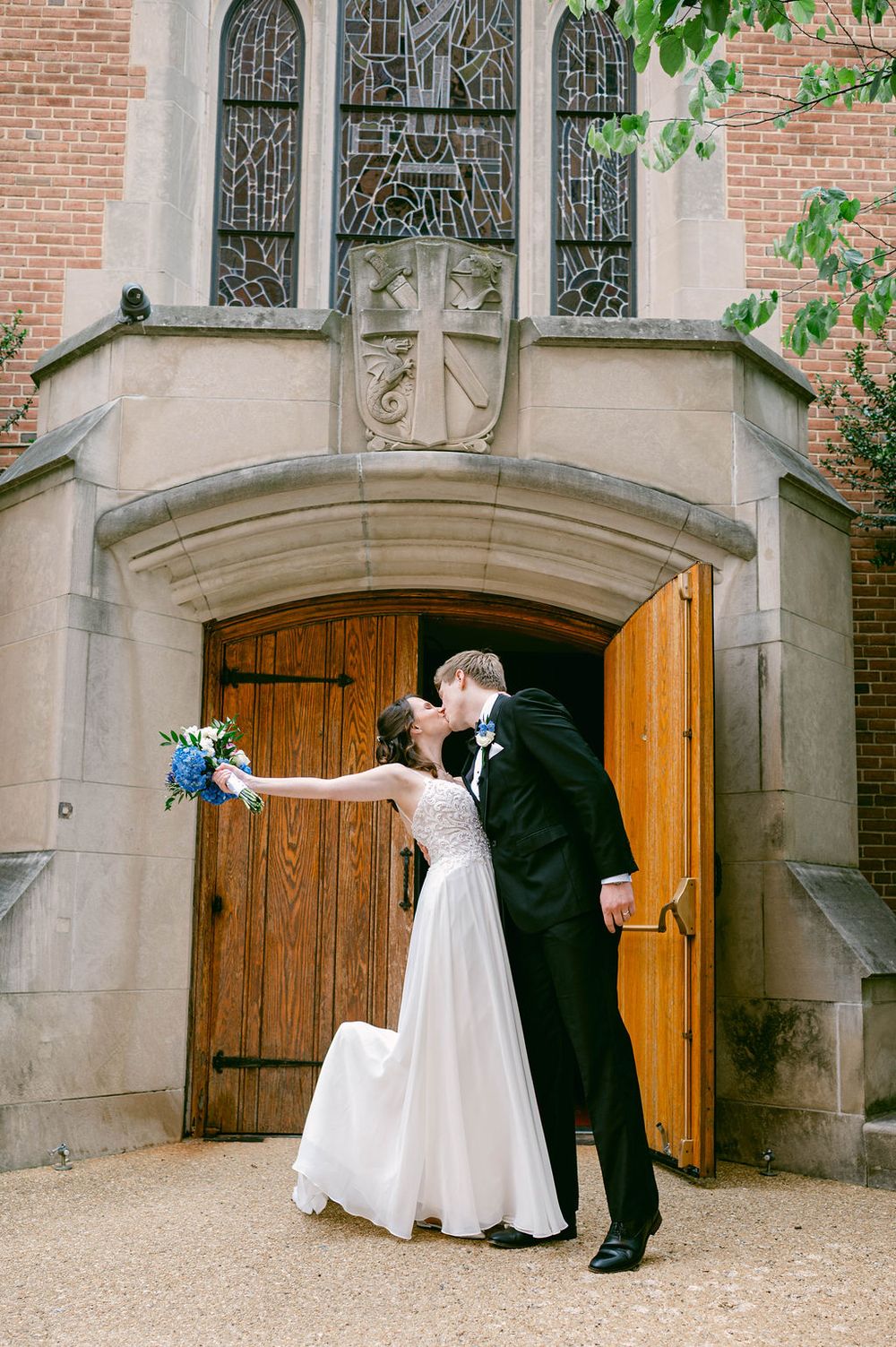 A romantic wedding sequence shows a couple in formal attire posing playfully by wooden church doors.