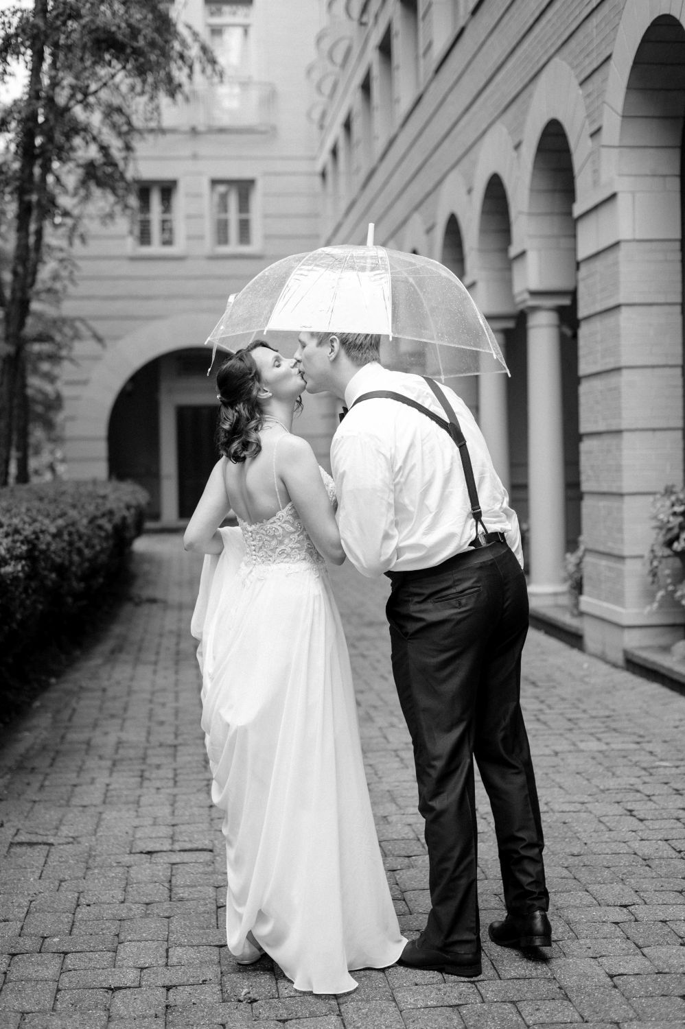 A black and white series of wedding photos showing a couple walking through an elegant stone archway corridor.