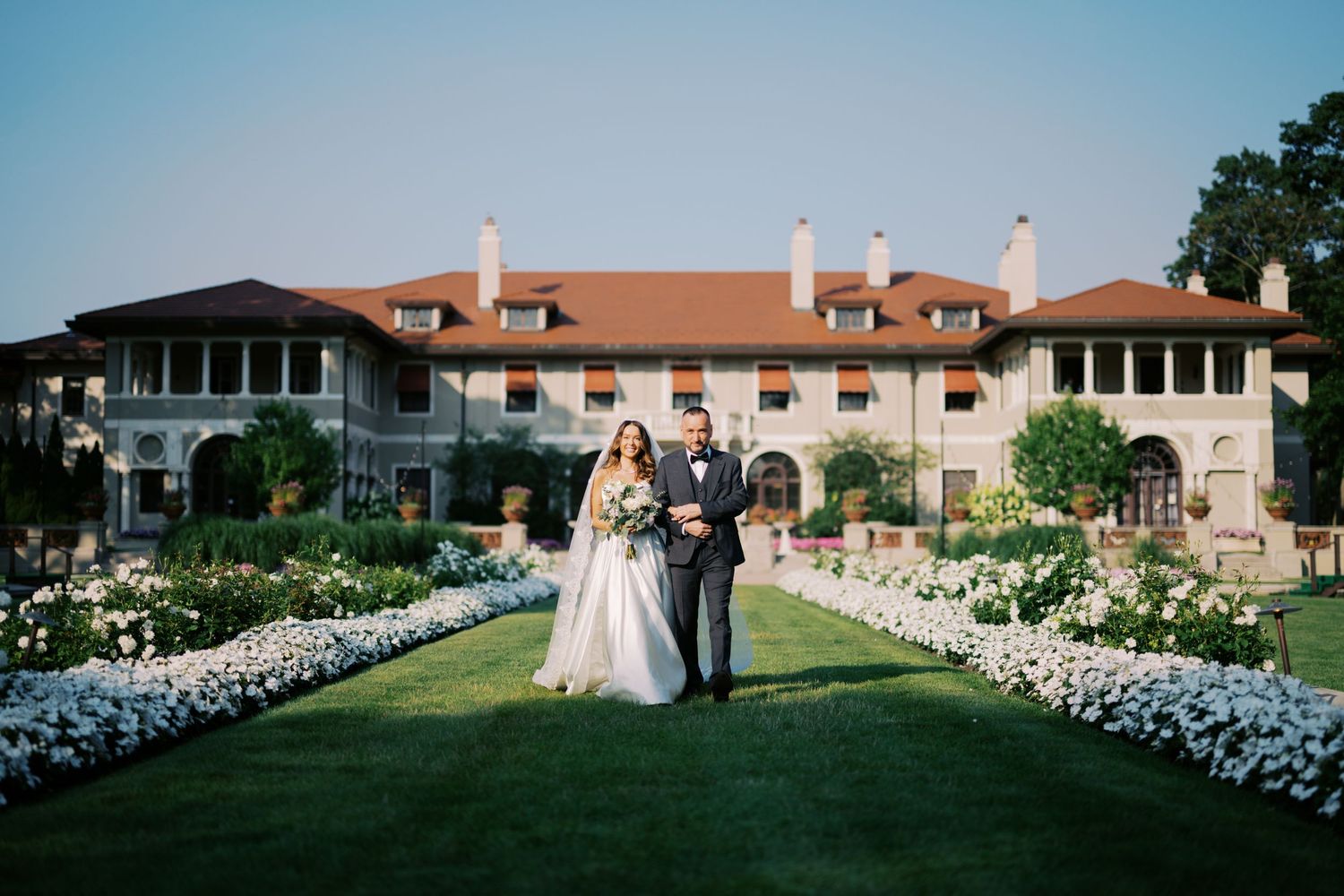 Panoramic sequence of an outdoor wedding ceremony with white flower petals lining a grassy aisle at sunset.