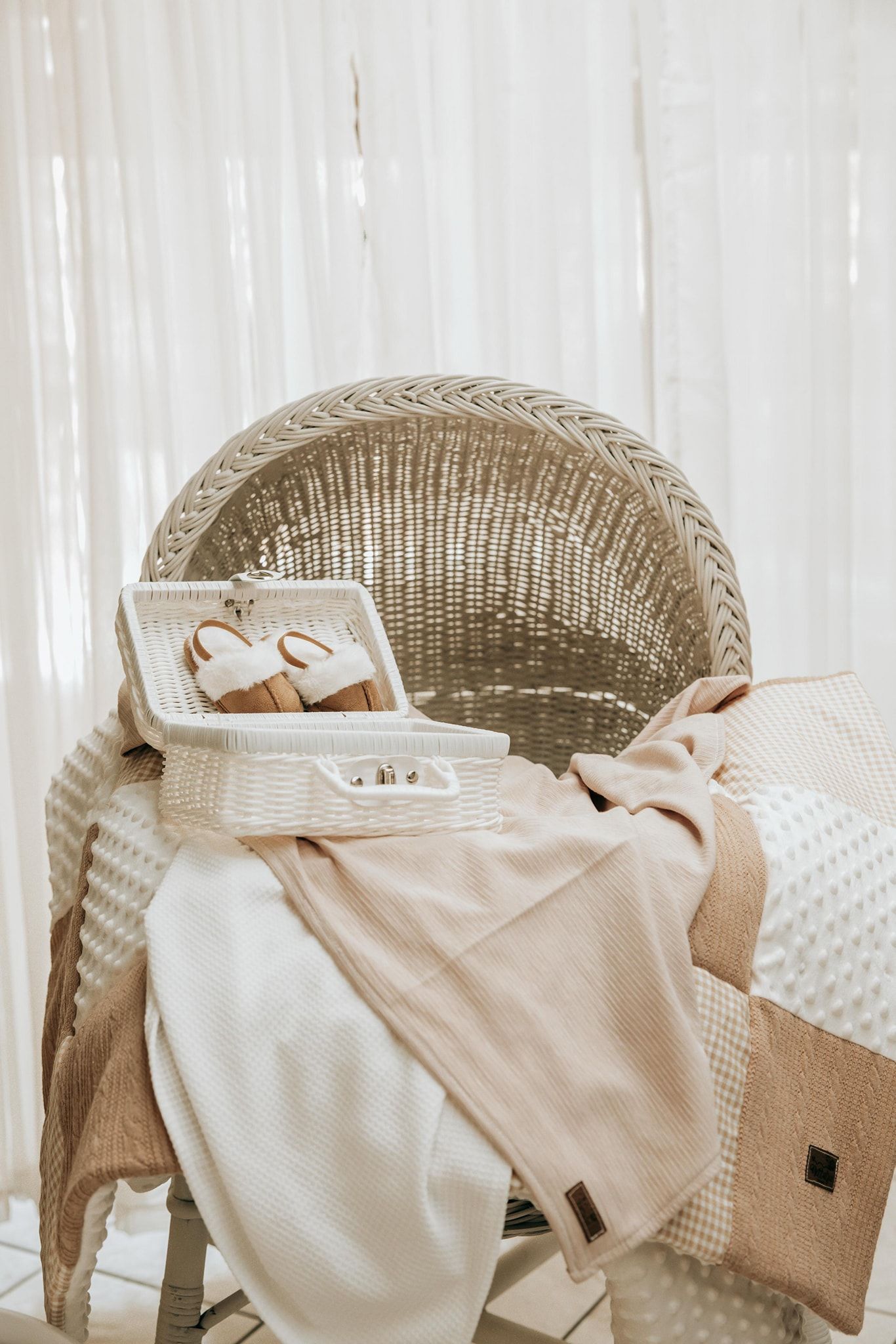 Wicker baskets filled with neatly folded white and beige linens against a light curtained background.
