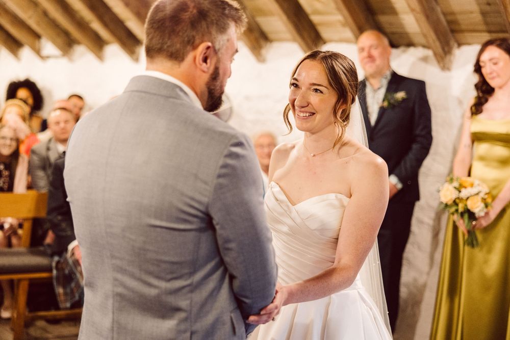 Newlyweds share their first dance in a rustic wooden barn venue surrounded by joyful wedding guests.