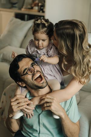 A playful series of candid moments between a parent and child showing affection and laughter on a light colored bed.