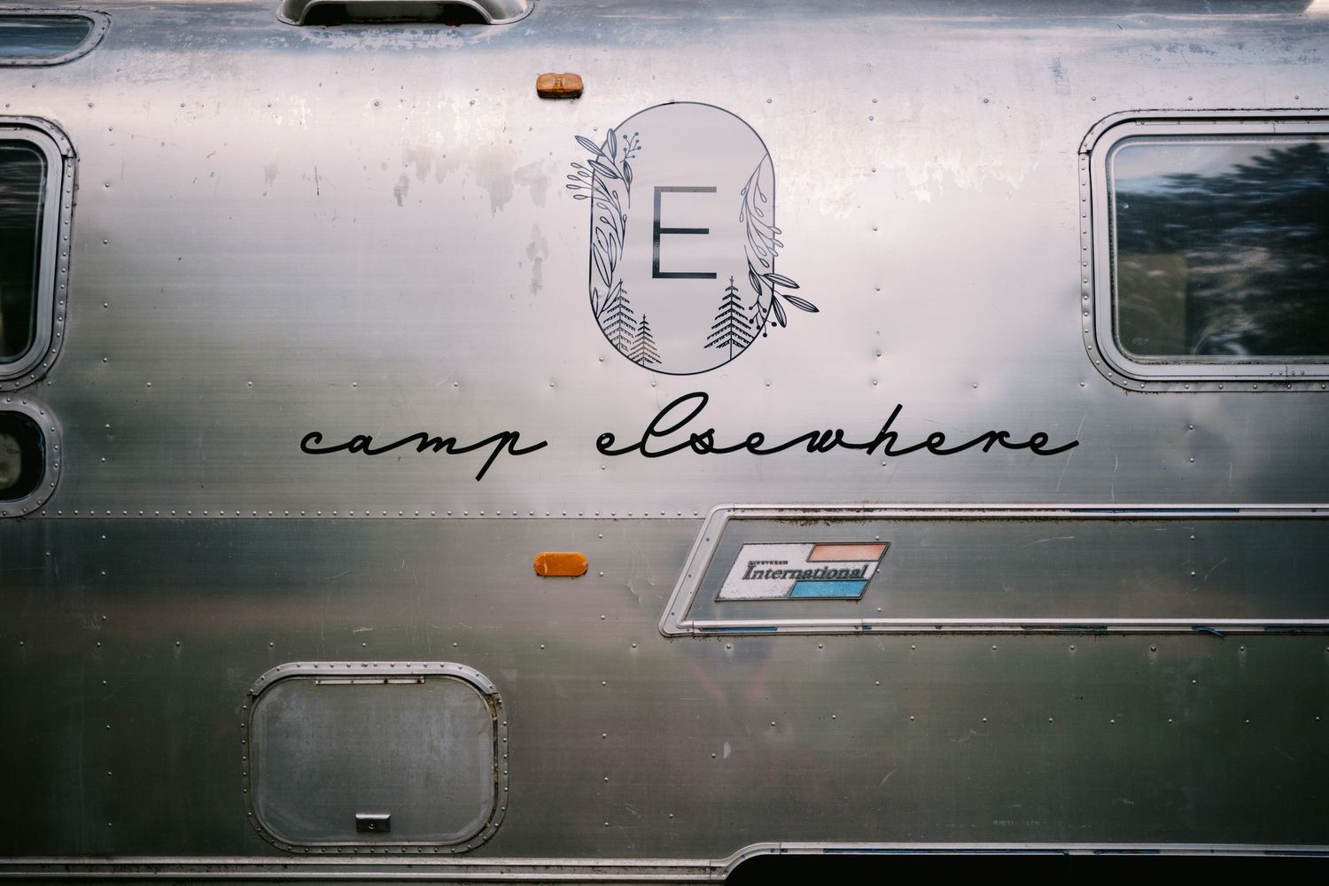 A series of vintage Airstream travel trailers lined up side by side showing their distinctive silver aluminum exteriors.