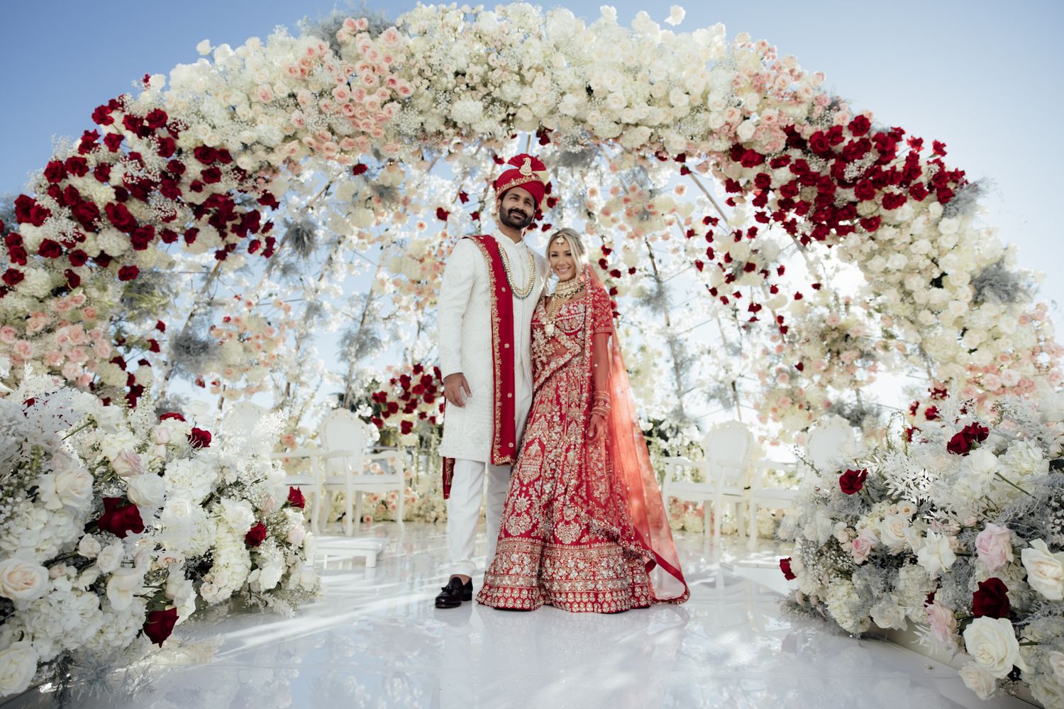 Elegant wedding ceremony setup with luxurious white floral arch and hanging crystal decorations against neutral backdrop.