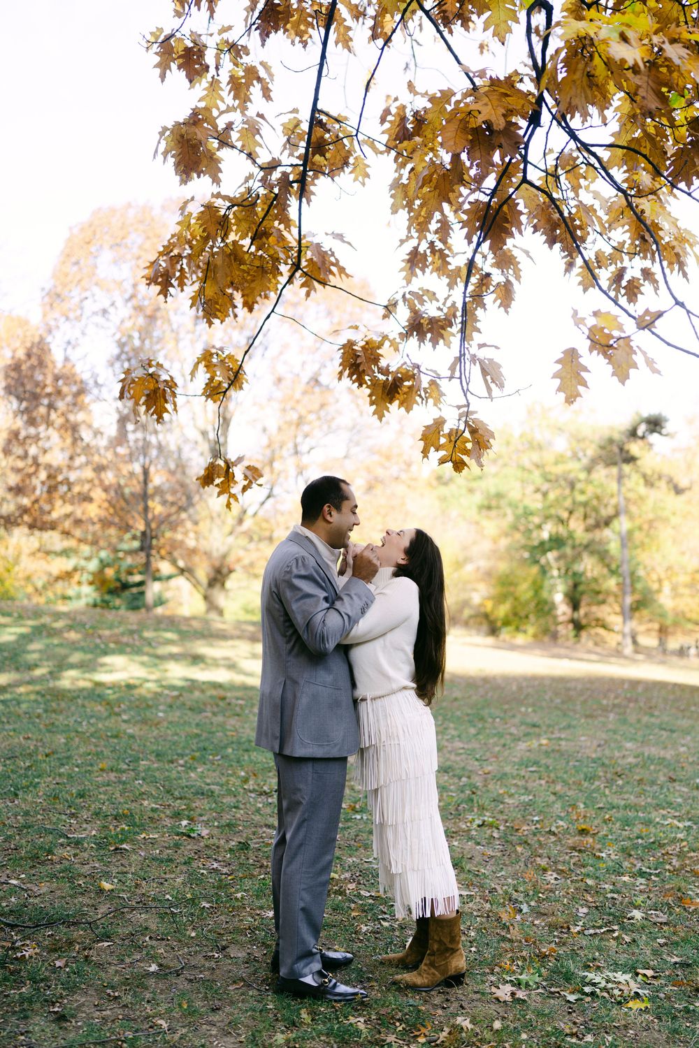 A romantic autumn photo session under golden leaves in a park setting.