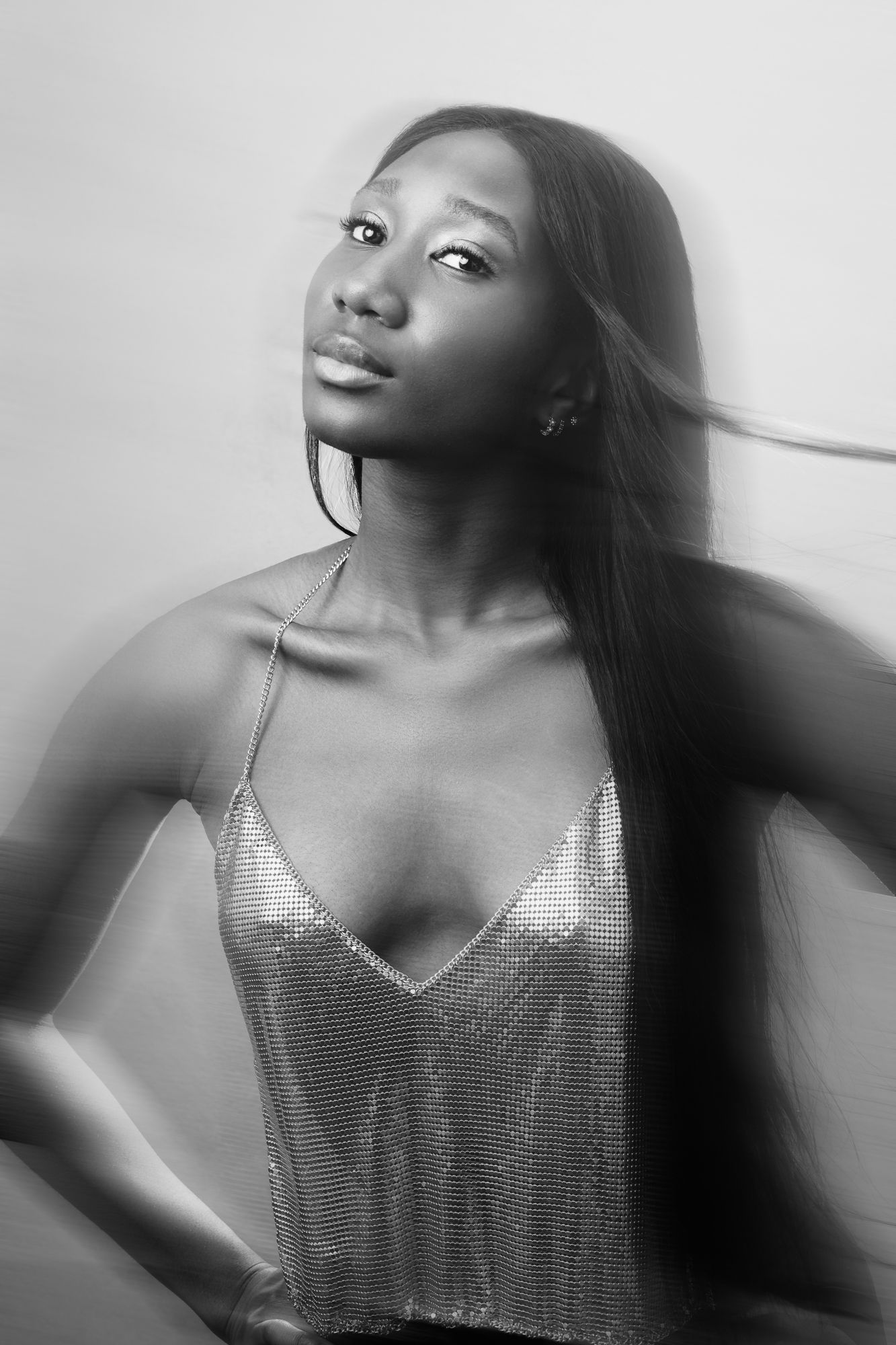 Black and white portrait of a person in a metallic silver top with long flowing hair gazing upward.