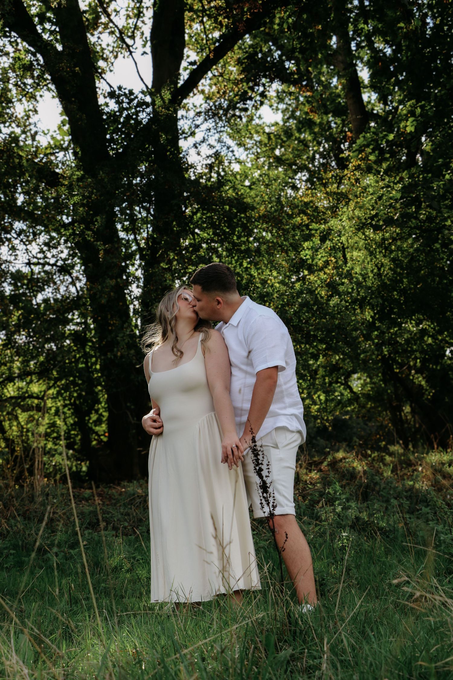 A romantic silhouette of a couple embracing in a misty forest with sunlight streaming through the trees.